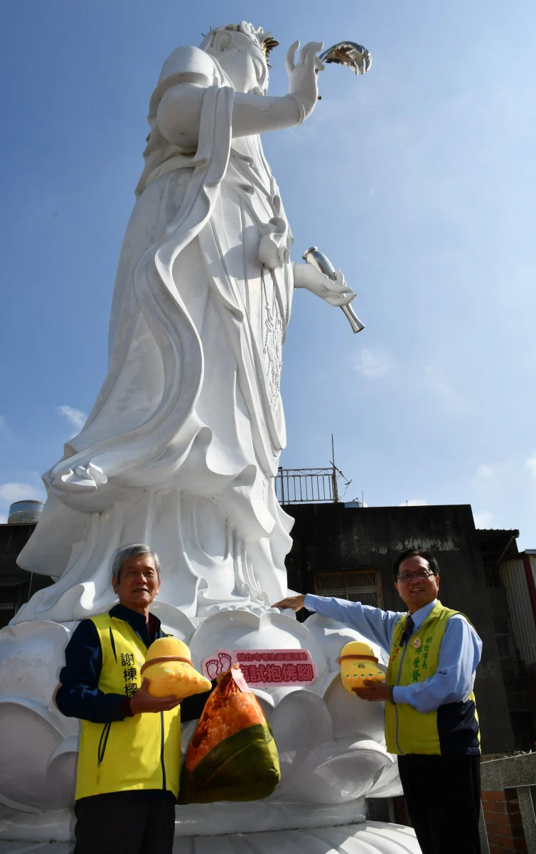 林世賢市長在開化寺樓頂的8公尺高大觀音聖像旁示範如何「抱佛腳」祈求觀音媽加持。圖／彰化市公所提供