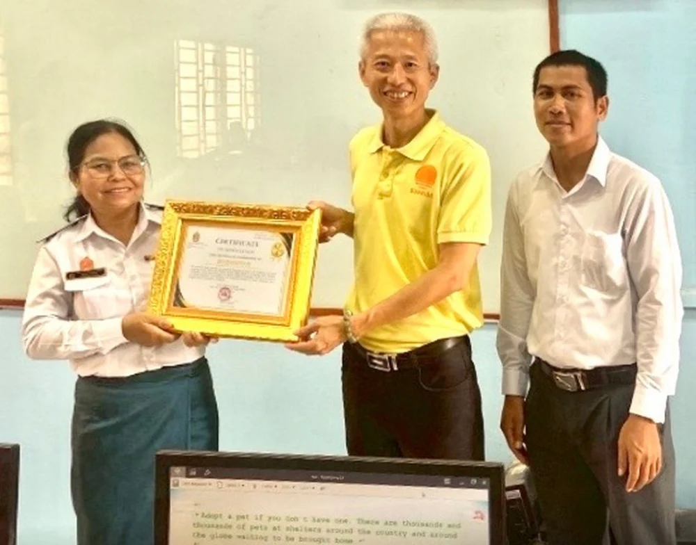 受助學校Hun Sen Phnom Sruoch High School校長(左)，傑出校友李政鍠博士(中)代表暨大，於該校致贈感謝狀儀式中合影。（暨大提供）