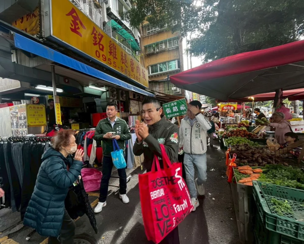 圖／張銘祐一行人沿途發送春聯與文宣品，向市場攤商與在地鄉親拜年致意。（張銘祐提供）