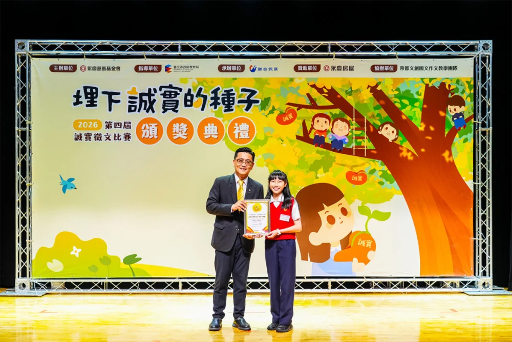 再興小學孫語暄(右)連續4年站上得獎舞台，永慶房屋副總經理簡國維(左)特頒「誠實典範特別獎學金」給予鼓勵。